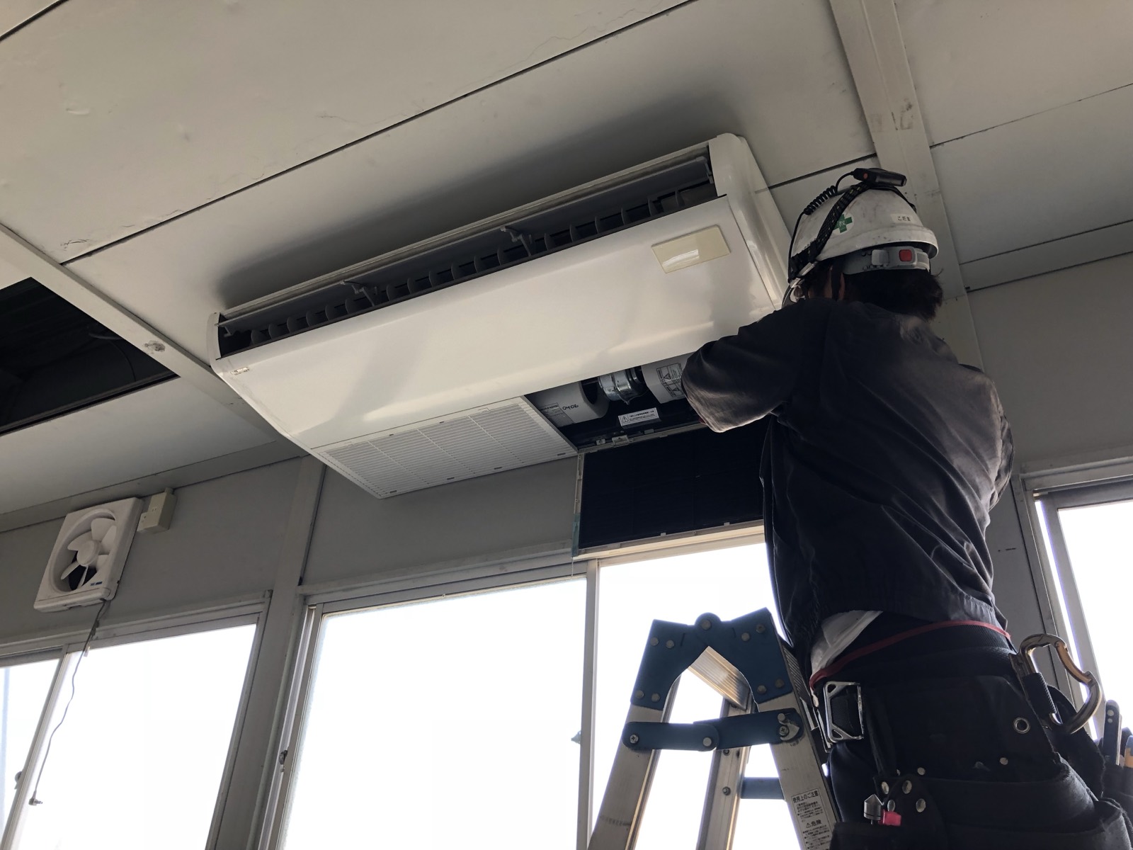 天井吊り形エアコンを点検する作業員